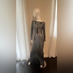 a mannequin wearing a black and white dress in front of curtained windows