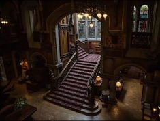 an ornate staircase leading up to the second floor with chandeliers and stained glass windows