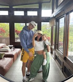 a man and woman taking a selfie in front of a large room with lots of windows