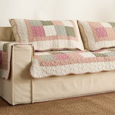 a couch with two pillows on top of it in front of a rug and wall