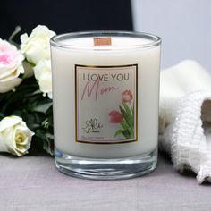 a white candle sitting on top of a table next to some flowers and a towel