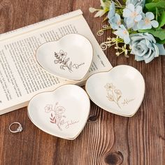 three heart shaped dishes sitting on top of a wooden table next to an open book