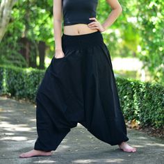 a woman in black pants and crop top posing for the camera with her hands on her hips