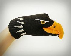 a hand with a black and yellow bird glove on it's palm, which has an orange beak