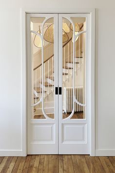 an empty room with two white doors and wooden floors