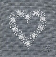 a cross stitched heart with small white flowers in the center on a gray background