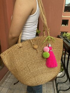 a woman carrying a straw bag with pom - poms