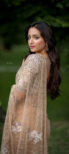 a beautiful woman in a sheer dress posing for the camera with her hands on her hips