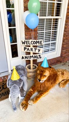 two stuffed animals sitting in front of a welcome party sign with balloons and an elephant