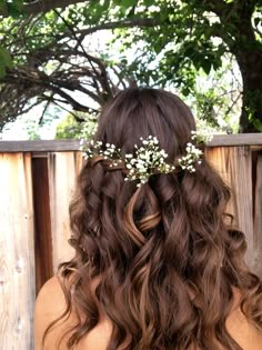 the back of a woman's head with long hair and flowers in her hair