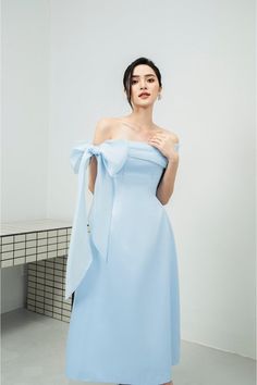 Possesses a basic dress form that helps to flatter the curves of the body A very simple but extremely poetic design with a drop shoulder design, knotted to create a lovely bowtie. Pastel blue tones express pure, gentle beauty, bringing a sense of peace. Product Details - Product type: Midi Dress- Material: Organza, Taffeta- Draped off-shoulder - Big bowtie at the shoulder - Fitted waist - A-line skirt - Length: 115cm Size & Fit - Model wears size: S- Model measurement: 170cm, 86-62-88 Care Instr Bowtie Dress, Hijab Prom Dress, Chinese Fancy Dress, Bow Tie Dress, Mean Blvd, Elegant Dresses Classy, Basic Dress, Fashion Mistakes, Prom Dresses Blue