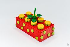 a red box with yellow and green knobs on it's lid is sitting in front of a white background