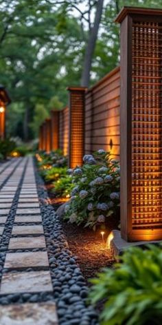 an outdoor garden area with lights and plants on either side of the walkway, along with stone pavers