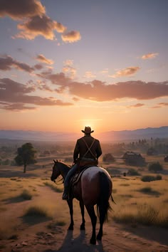 a man riding on the back of a brown horse across a desert field at sunset