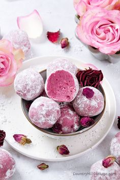 powdered sugar covered donuts on a plate with pink roses and petals around them