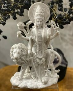 a statue of the hindu god with two lions in front of it on a table