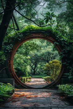 the entrance to a lush green park with lots of trees and bushes on either side