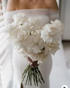 a bride holding a bouquet of white flowers