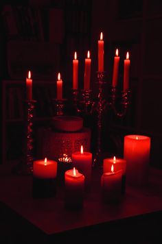 lit candles are arranged on a table in front of a bookshelf