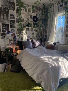 an unmade bed sitting in a bedroom next to a window with lots of pictures on the wall