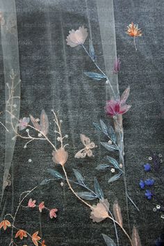 some flowers and leaves on a black cloth with sheer fabric behind them, as seen through the window