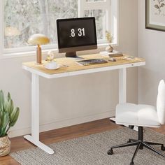 a desk with a computer on it in front of a window and a plant next to it