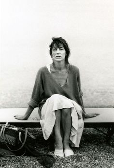 a black and white photo of a woman sitting on a bench