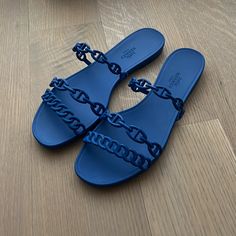 a pair of blue sandals with chains on the bottom and one in the middle sitting on a wooden floor