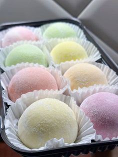 there are many different types of desserts in the tray on the table and one is pink, green, yellow, and white