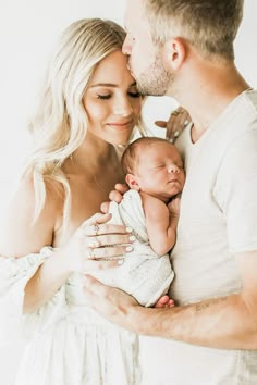 a man and woman holding a baby in their arms