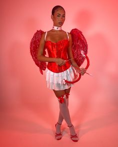 a woman dressed in red and white with wings on her head, holding an umbrella