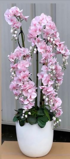 pink flowers are in a white vase on a table