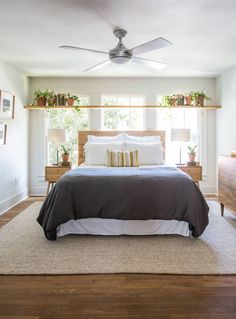 a bedroom with a bed, nightstands and ceiling fan in it's center