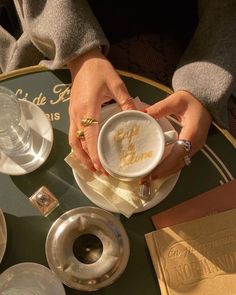 a person is holding a cup on a table with plates and napkins around it