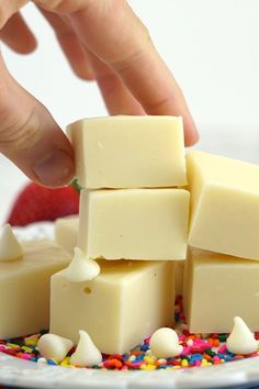 a person picking up pieces of white chocolate from a plate with sprinkles