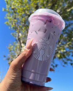 a woman's hand holding a purple starbucks cup