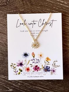 a necklace with flowers on it and the words look into chaos written in gold lettering