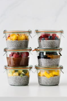 four glass containers filled with different types of fruits and vegetables on top of each other