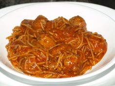 a white bowl filled with spaghetti and meatballs