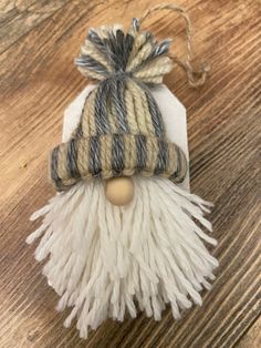 a small white and gray hat on top of a wooden table next to a string ornament