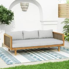 a couch sitting on top of a rug next to a potted plant in a yard