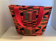 Kente fabric bucket tote bag.  Great for everyday, for shopping it can be used as a storage bag for bathroom items or cosmetics and for shopping.  Ships from Burlington, North Carolina.  The width across the top is 16 inches, the height is 11 inches and the depth on the side bottom in 4 inches.  African  cloth/fabric.  Great for a gift.  Great as a book bag or for a grocery bag, Orange Large Capacity Tote Shoulder Bag, Large Capacity Orange Bag For Shopping, Large Capacity Orange Tote Shoulder Bag, Orange Large Capacity Square Bag, Large Capacity Square Orange Bag, Large Capacity Orange Square Bag, Casual Orange Shoulder Bag For Shopping, Orange Rectangular Bucket Bag For Shopping, Orange Bucket Bag With Large Capacity For Everyday Use