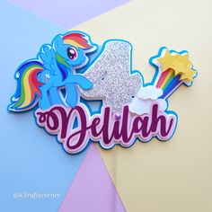 a birthday cake topper with the number four on it and a rainbow pony in the middle