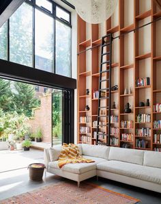 a living room filled with lots of books and furniture next to a large open window