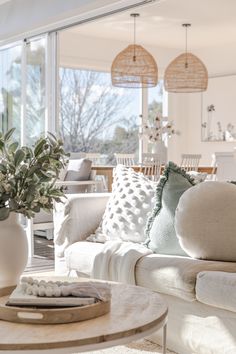 a living room filled with white furniture and lots of pillows on top of the couches