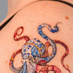 an octopus tattoo on the back of a woman's stomach, with blue and red designs