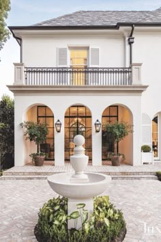 a large white house with a fountain in the front yard