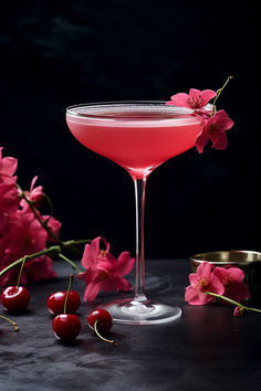 a pink cocktail with cherry garnish on the rim and cherries next to it