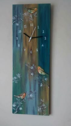 a clock with birds painted on it is hanging on the wall next to a plant