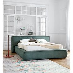 a large bed sitting on top of a hard wood floor next to a white wall